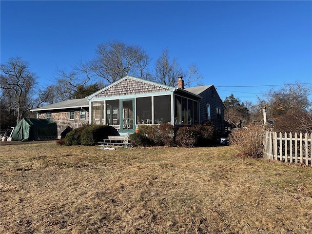 rear view of property featuring a lawn and a sunroom