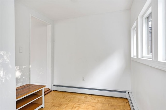 spare room with a healthy amount of sunlight, baseboard heating, and light parquet flooring