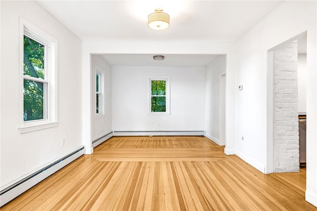 spare room with a baseboard heating unit, a wealth of natural light, and wood-type flooring