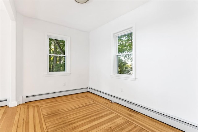 unfurnished room featuring baseboard heating and hardwood / wood-style flooring