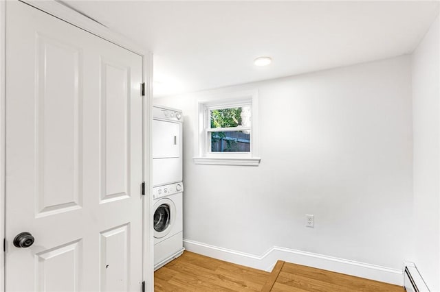 laundry room featuring stacked washer and clothes dryer, a baseboard radiator, and hardwood / wood-style floors