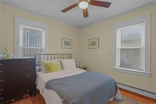 bedroom with ceiling fan, light hardwood / wood-style flooring, crown molding, and a baseboard heating unit