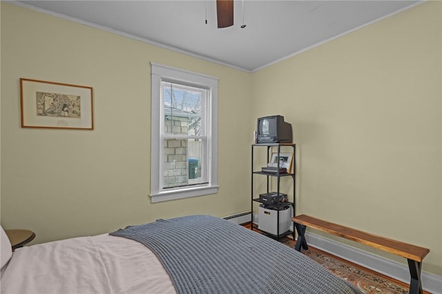 bedroom featuring wood-type flooring, a baseboard heating unit, ceiling fan, and ornamental molding