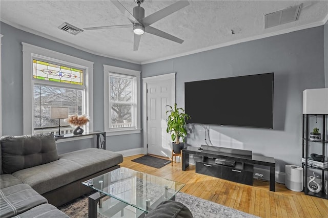 living room featuring hardwood / wood-style flooring, a textured ceiling, ceiling fan, and ornamental molding