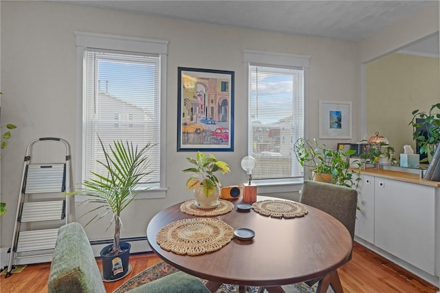 dining area with a baseboard heating unit and light hardwood / wood-style floors