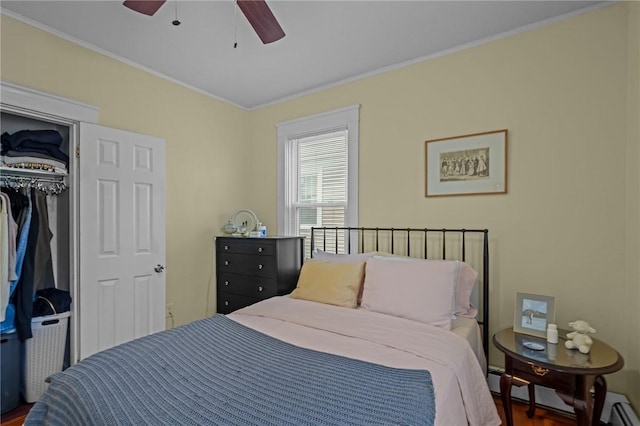 bedroom with ceiling fan, ornamental molding, a baseboard heating unit, a closet, and dark hardwood / wood-style floors