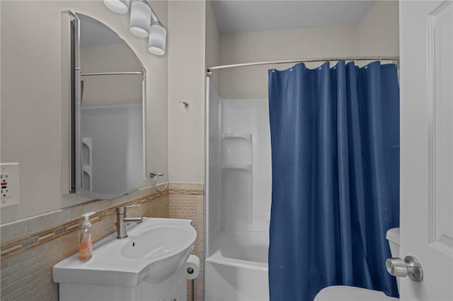 full bathroom with tile walls, vanity, shower / bath combo with shower curtain, and toilet