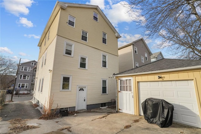 back of house featuring a garage and an outbuilding