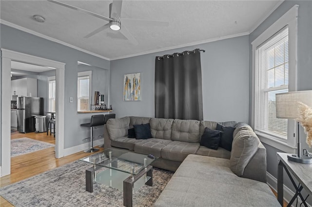 living room with wood-type flooring, ornamental molding, and plenty of natural light