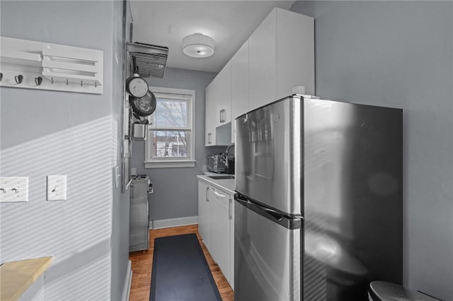 kitchen featuring stainless steel refrigerator, white cabinets, sink, and hardwood / wood-style floors