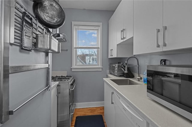 kitchen with white cabinets, stainless steel appliances, sink, and wood-type flooring