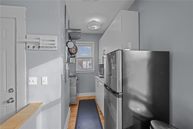 kitchen with white cabinetry, light wood-type flooring, and stainless steel fridge