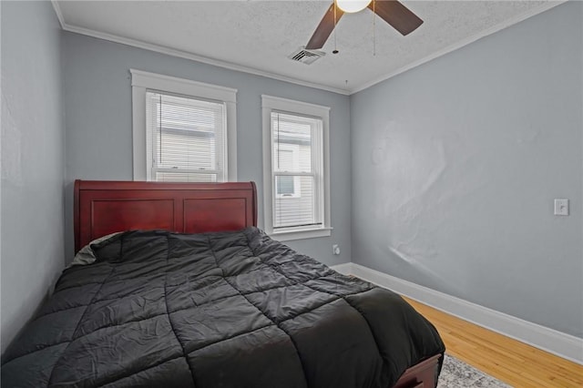 bedroom with wood-type flooring, a textured ceiling, ceiling fan, and ornamental molding