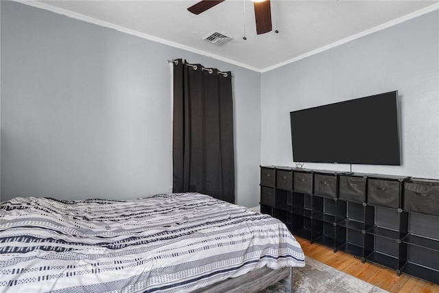 bedroom featuring ceiling fan, crown molding, and hardwood / wood-style flooring