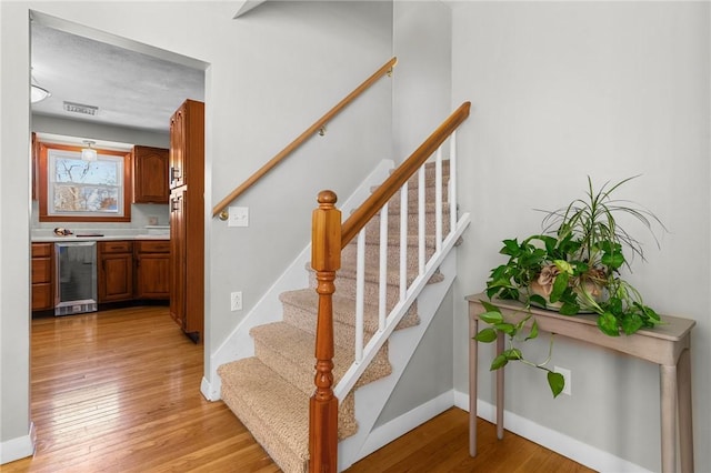 stairway featuring hardwood / wood-style floors and beverage cooler