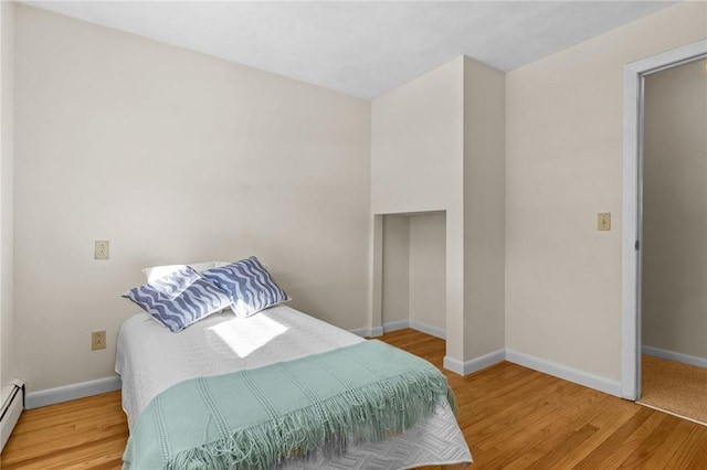 bedroom featuring hardwood / wood-style floors and baseboard heating