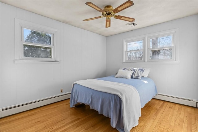 bedroom with a baseboard heating unit, light hardwood / wood-style flooring, and ceiling fan