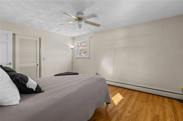 bedroom with ceiling fan, a baseboard radiator, a closet, and light hardwood / wood-style flooring