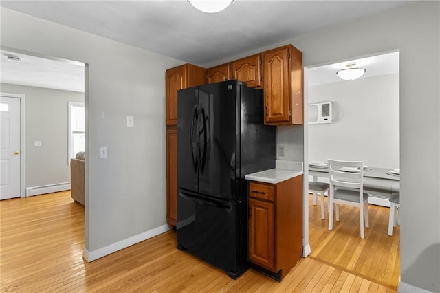 kitchen with black refrigerator, light hardwood / wood-style floors, and baseboard heating