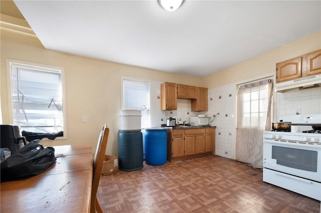 kitchen with white appliances, dark parquet floors, light brown cabinetry, and decorative backsplash