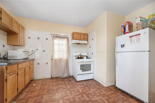 kitchen with white appliances, parquet flooring, backsplash, and sink