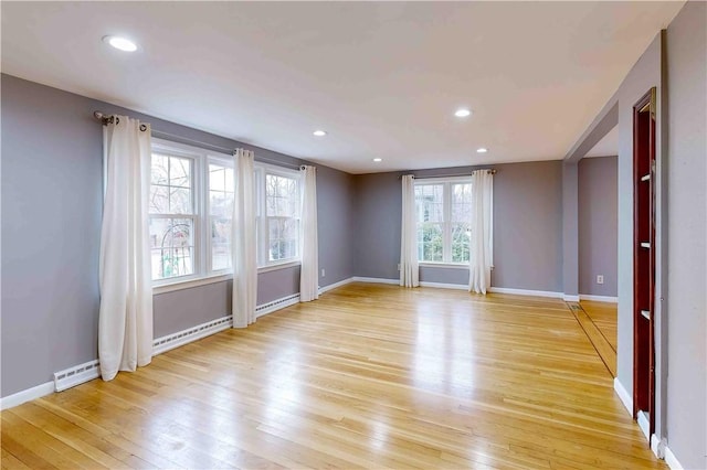 unfurnished room featuring light wood-type flooring and a baseboard radiator