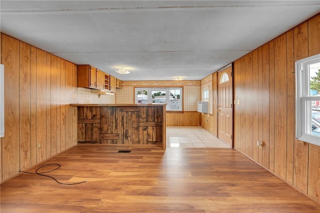 kitchen with a healthy amount of sunlight, wooden walls, and kitchen peninsula