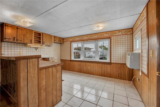 kitchen with kitchen peninsula, a textured ceiling, and light tile patterned floors