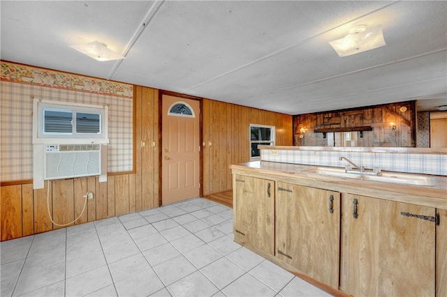 kitchen featuring sink, wooden walls, light tile patterned flooring, and a wall unit AC