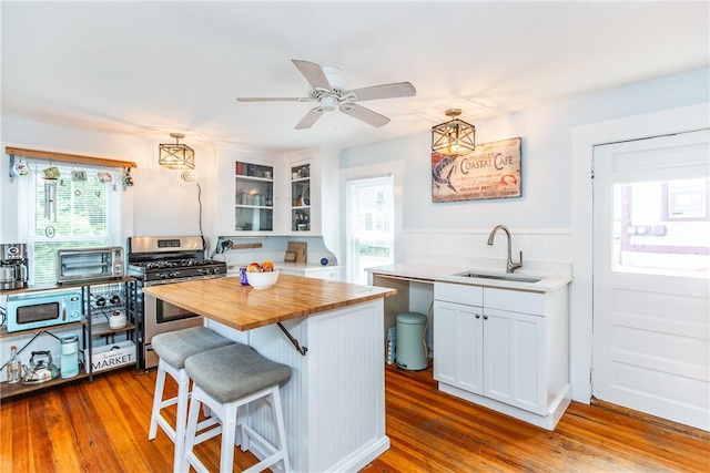 kitchen featuring white cabinetry, stainless steel range with gas cooktop, a breakfast bar area, and sink