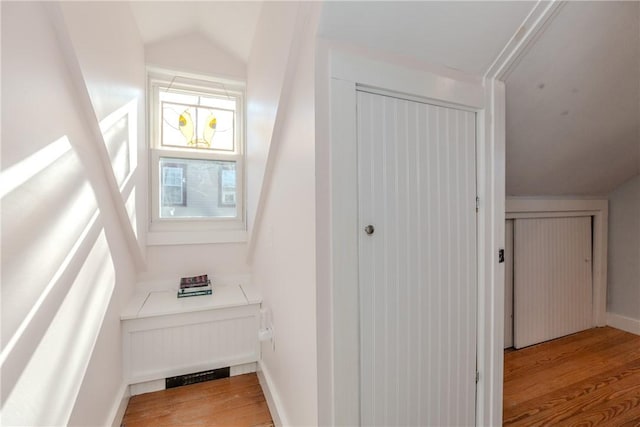 additional living space with vaulted ceiling and light hardwood / wood-style flooring