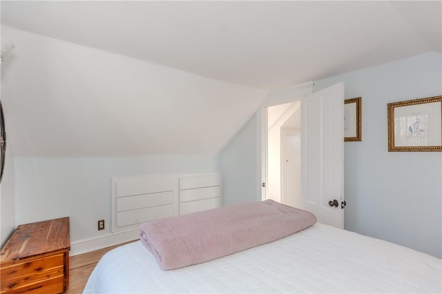 bedroom with vaulted ceiling and light hardwood / wood-style flooring