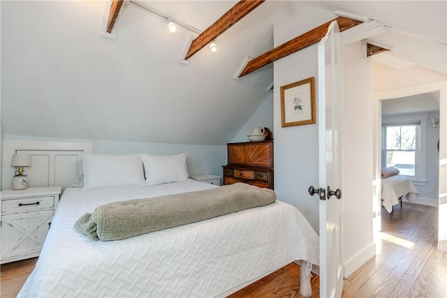 bedroom with light hardwood / wood-style floors and lofted ceiling with beams