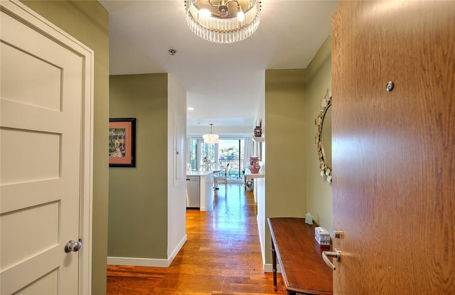 corridor with a notable chandelier and hardwood / wood-style floors