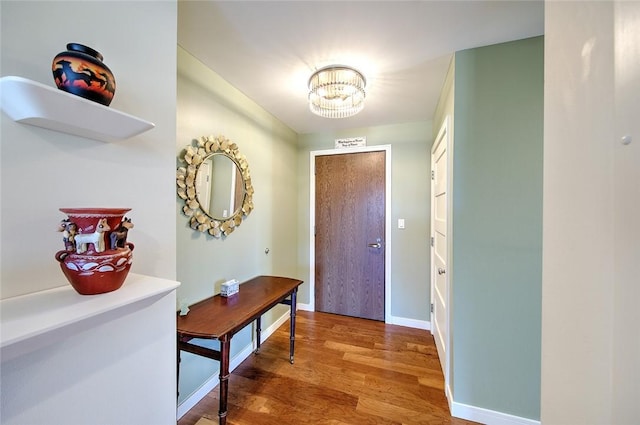 foyer entrance featuring wood-type flooring and a chandelier