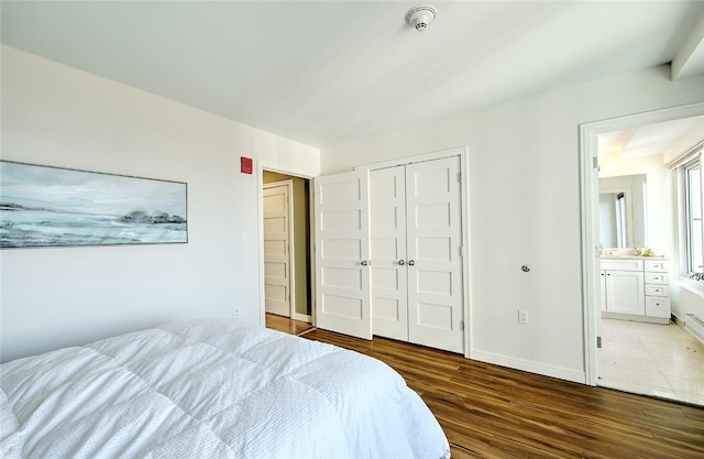 bedroom with dark hardwood / wood-style flooring, a closet, and connected bathroom