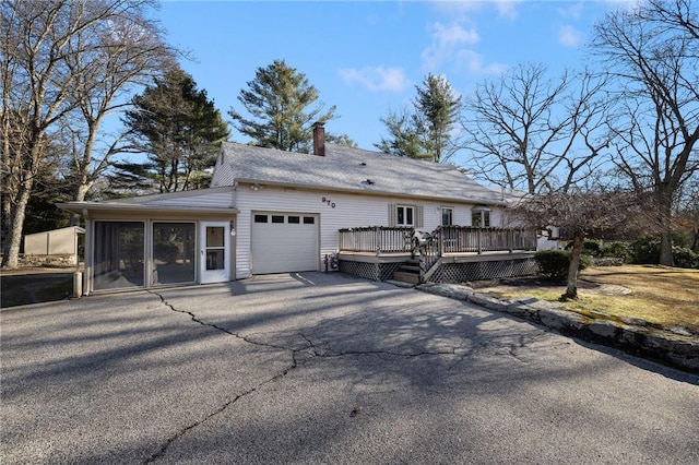 view of front of property with a sunroom, a garage, and a wooden deck