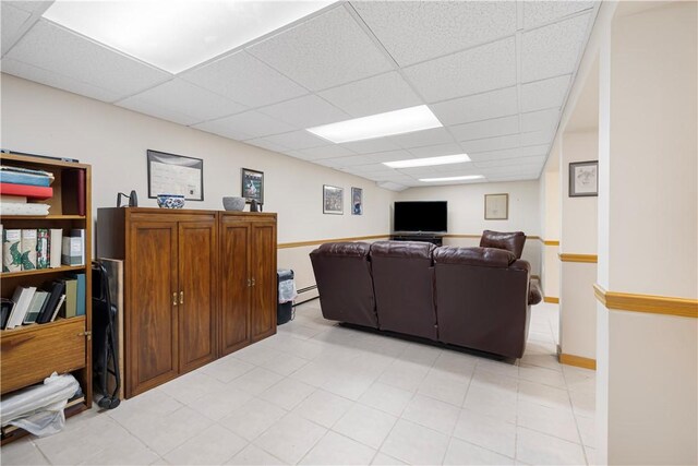 living room featuring a paneled ceiling and baseboard heating