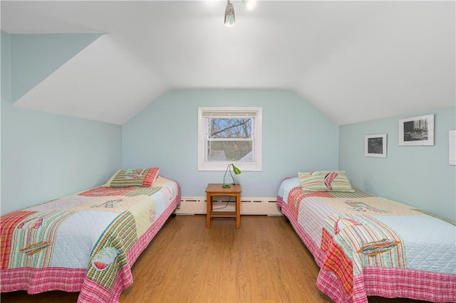 bedroom with lofted ceiling, a baseboard heating unit, and light wood-type flooring