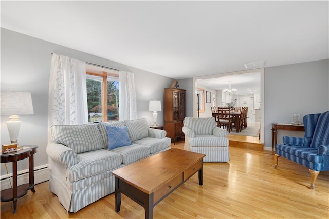 living room with a baseboard radiator, a chandelier, and light hardwood / wood-style floors