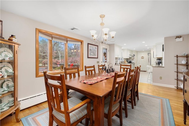 dining room featuring a notable chandelier, light wood-type flooring, and a baseboard radiator