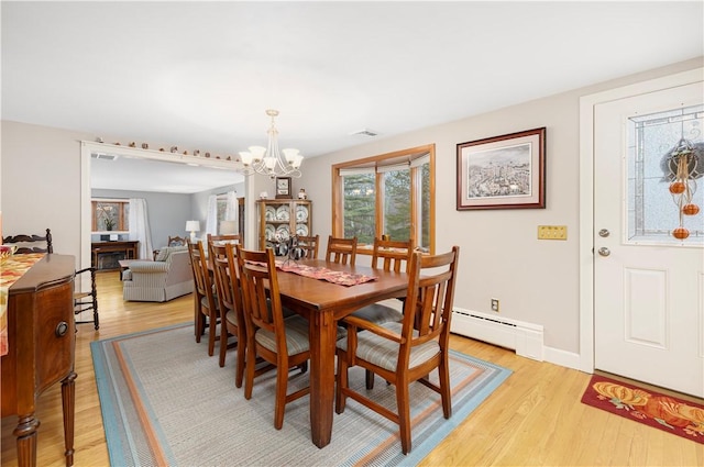 dining space with a notable chandelier, a baseboard radiator, and light hardwood / wood-style flooring