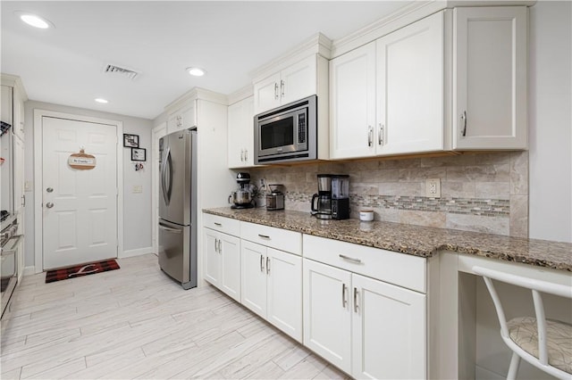 kitchen featuring white cabinets, stone countertops, and appliances with stainless steel finishes