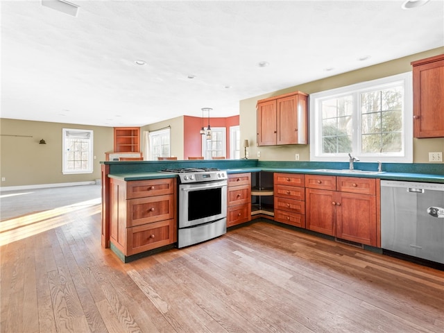 kitchen with kitchen peninsula, light hardwood / wood-style flooring, pendant lighting, appliances with stainless steel finishes, and sink