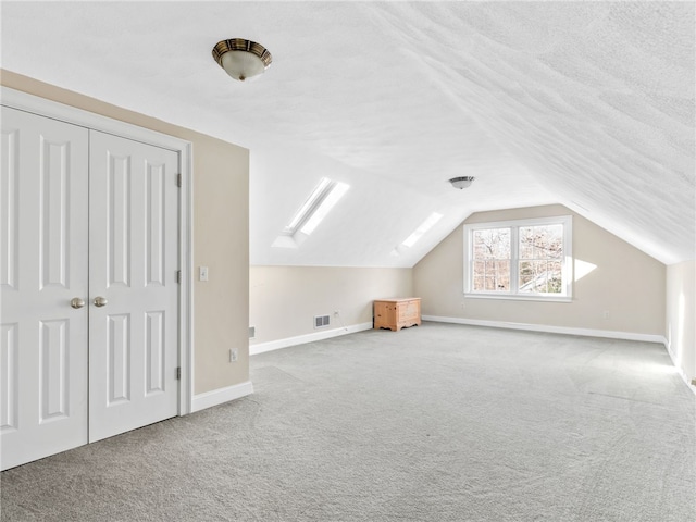 bonus room with a textured ceiling, carpet, and vaulted ceiling with skylight