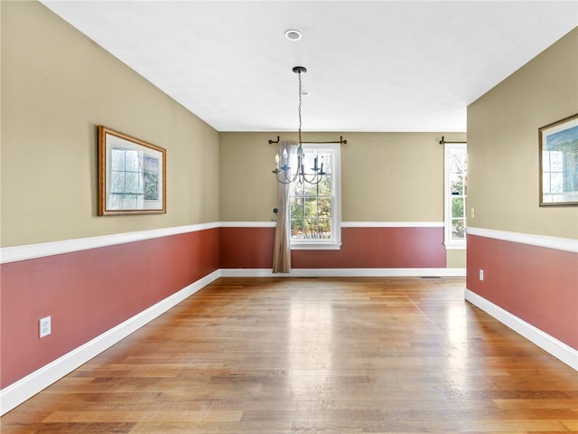 unfurnished dining area with a notable chandelier and light wood-type flooring