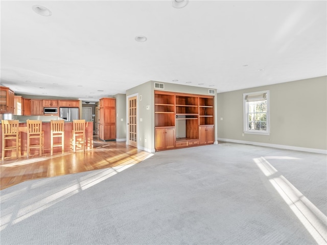 unfurnished living room featuring light colored carpet