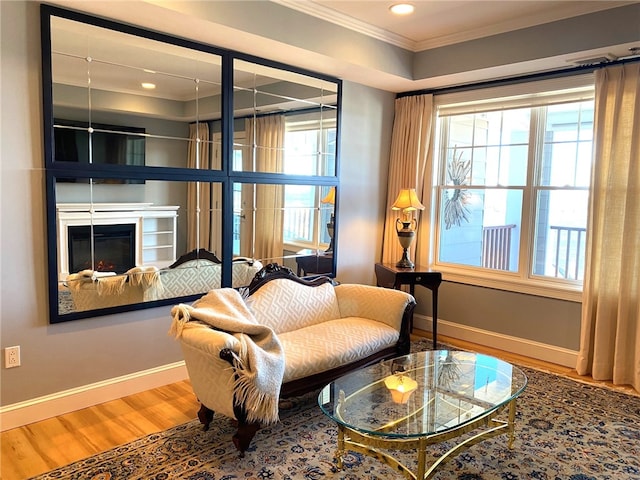 sitting room with a healthy amount of sunlight, ornamental molding, and hardwood / wood-style floors