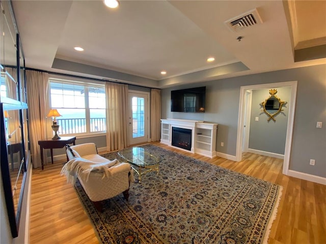 living room with light hardwood / wood-style flooring and a tray ceiling