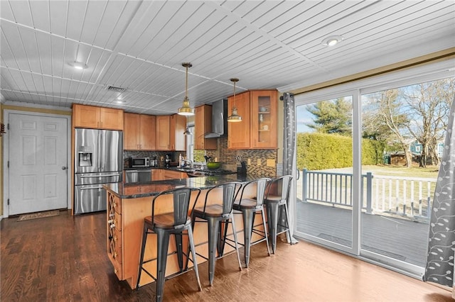 kitchen with decorative light fixtures, stainless steel appliances, wall chimney range hood, dark hardwood / wood-style flooring, and sink